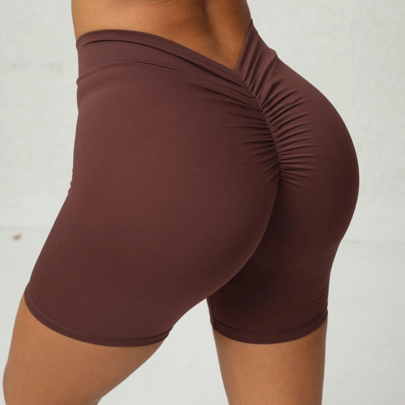 Woman wearing brown tight elastic sports shorts for yoga and gym, highlighting ruching detail on back. Style SF1050.