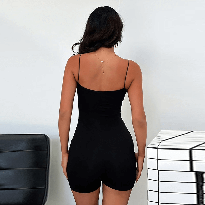 Back view of woman in black tight short jumpsuit with straps, showcasing sleek style and fashion-forward design.