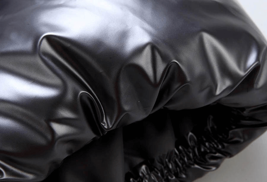 Close-up of sleek black nylon fabric on a women's hooded vest, showcasing the glossy texture and quality stitching.