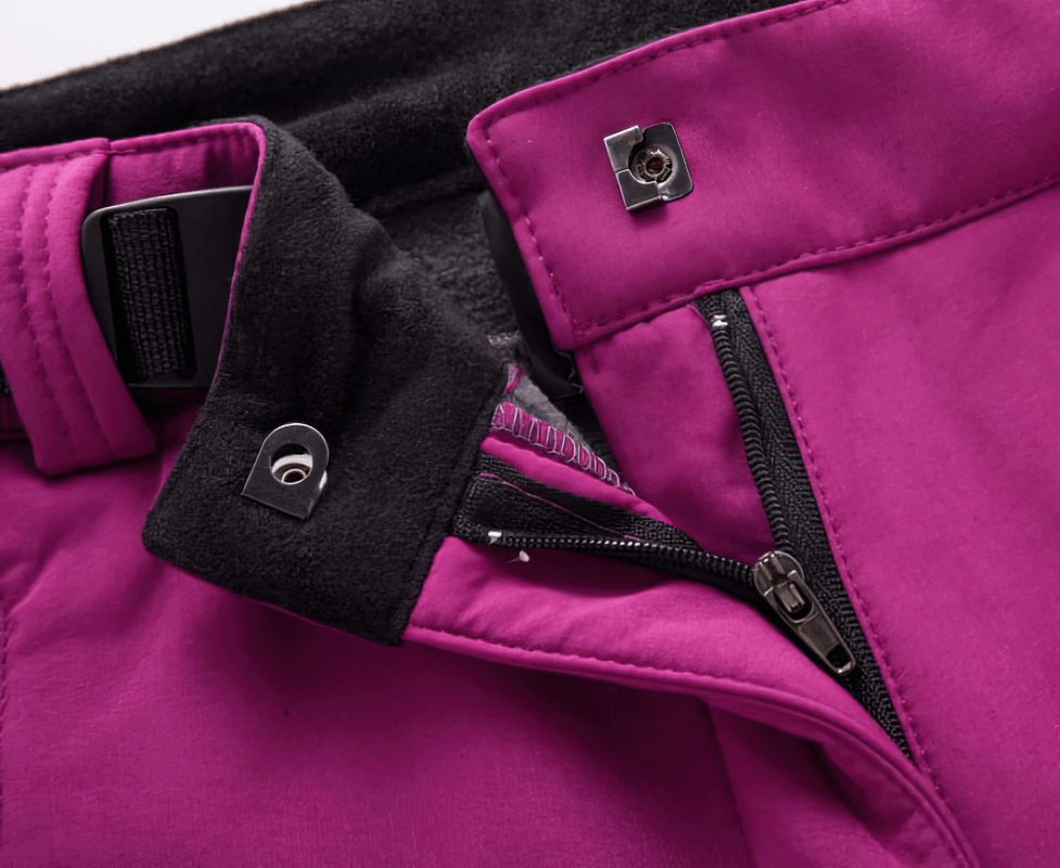Close-up of women's waterproof sports pants with zipper fly, showcasing durable polyester fabric in vibrant magenta color.