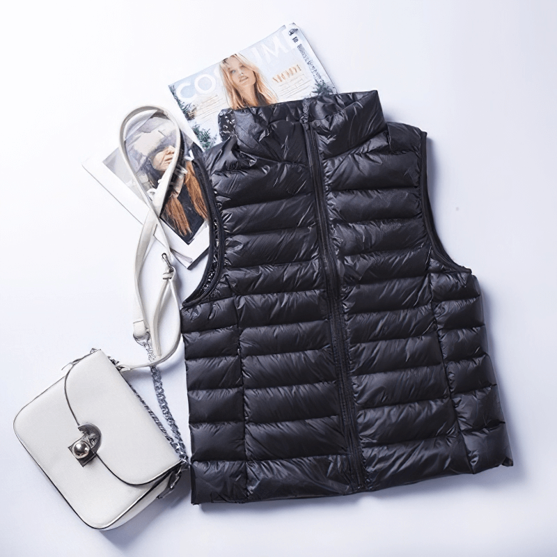 Women's black zipper windproof duck down vest with pockets displayed with handbag and magazine, style SF0116.