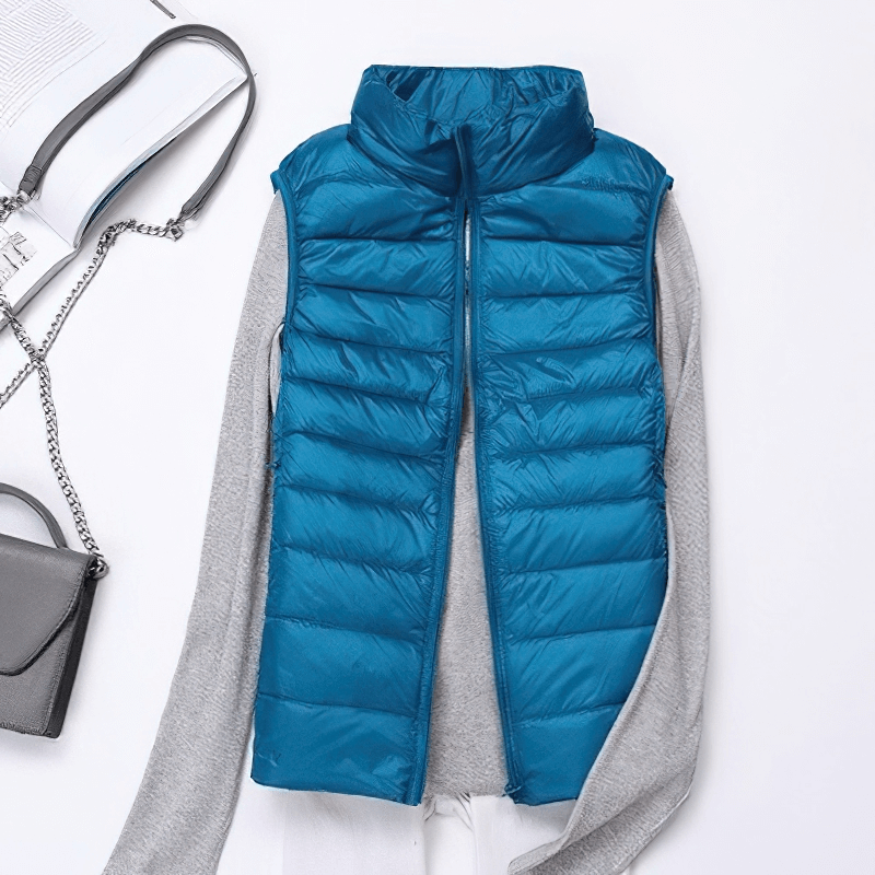 Women's blue windproof duck down vest with zipper and pockets, displayed on a gray shirt, showcasing style and comfort.