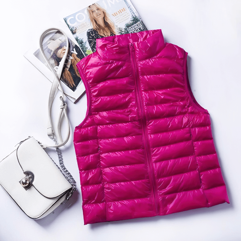 Fuchsia women's windproof duck down vest with zipper and pockets, perfect blend of style and comfort, displayed with white handbag and magazines.