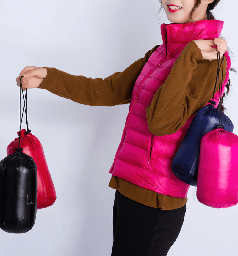 Woman wearing pink windproof duck down vest holding colorful pouch bags.