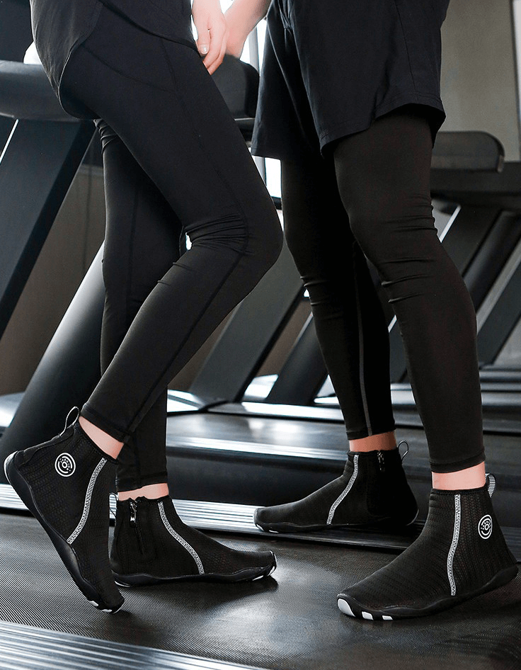 Two people in black Zipper Breathable Water Shoes, standing on a treadmill, showing non-slip rubber outsoles.