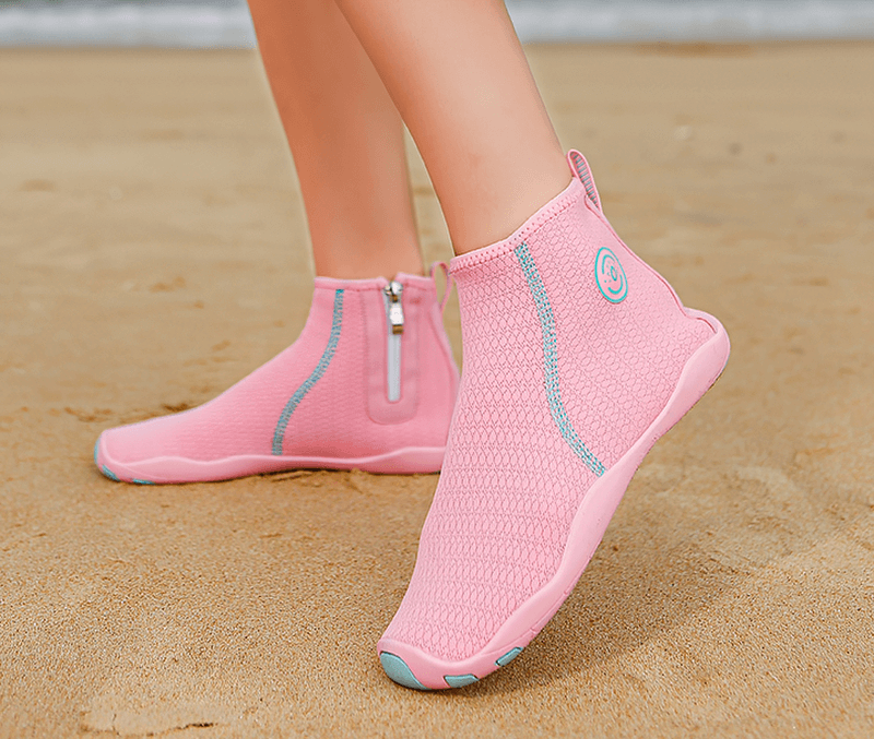 Person wearing pink zipper breathable water shoes for swimming on sandy beach.